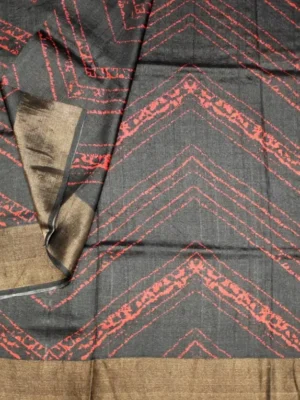 Close-up of brick red geometric print and Antique Gold Baavanchi border on Charcoal Black Pure Tussar Silk Saree
